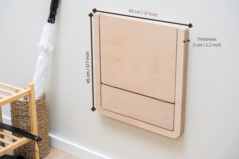May include: A light-colored, wall-mounted changing table made of wood. The table is 17 inches wide, 17.7 inches high, and 1.2 inches thick. The design is minimalist and modern, with rounded corners.