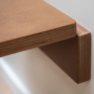 Puede incluir: Primer plano de una estanter&iacute;a de madera con un acabado de veta natural. La estanter&iacute;a est&aacute; montada en una pared, mostrando sus l&iacute;neas limpias y su dise&ntilde;o minimalista. El borde de la estanter&iacute;a es redondeado, a&ntilde;adiendo elegancia.