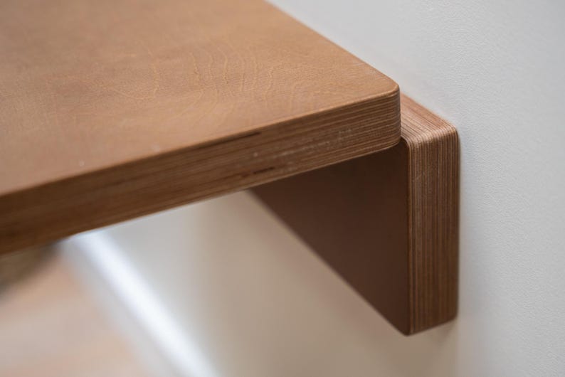 Puede incluir: Primer plano de una estanter&iacute;a de madera con un acabado de veta natural. La estanter&iacute;a est&aacute; montada en una pared, mostrando sus l&iacute;neas limpias y su dise&ntilde;o minimalista. El borde de la estanter&iacute;a es redondeado, a&ntilde;adiendo elegancia.