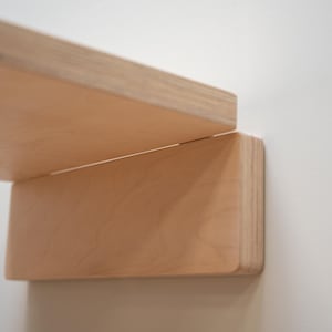 Close-up of folding mechanism and clean joint detail on minimalist birch plywood wall chair.