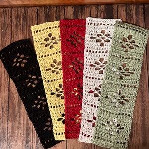 May include: Five crocheted bookmarks in different colors: black, yellow, red, white, and green. Each bookmark features a delicate floral pattern.