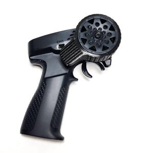 May include: Black RC transmitter with a textured grip and a wheel for control. The trigger and wheel are black. The transmitter has the text "CH3" on the top.