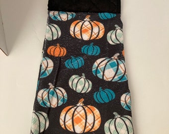 Plaid pumpkins on black background hanging kitchen towel with hot pad .