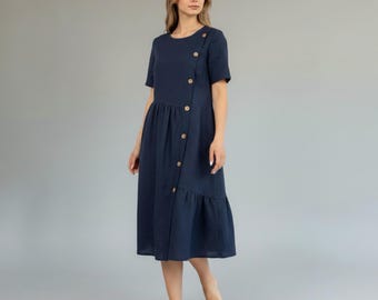 May include: A navy blue midi dress with short sleeves and a round neckline. The dress features a button-up closure on the bodice and a ruffled hem. The dress is made of a soft, flowing fabric.