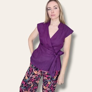Pode incluir: Um top roxo de amarrar com mangas curtas e um la&ccedil;o na cintura. O top &eacute; combinado com cal&ccedil;as de estampa floral.