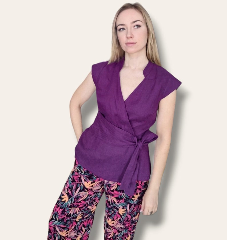 Pode incluir: Um top roxo de amarrar com mangas curtas e um la&ccedil;o na cintura. O top &eacute; combinado com cal&ccedil;as de estampa floral.