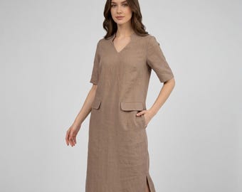 May include: A knee-length, taupe-colored dress with short sleeves and a V-neck. The dress features two front pockets and side slits. The fabric appears to be linen or a similar lightweight material, suitable for warm weather.