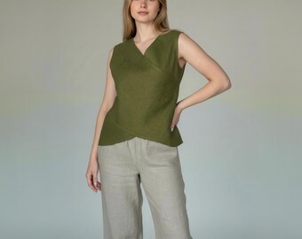 May include: Olive green sleeveless wrap top paired with light beige linen pants. The top features a V-neck and a wrap design. The pants are wide-legged and made of a light-colored fabric. The outfit is simple and elegant.