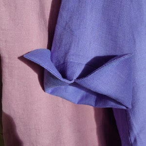 May include: Close-up of two fabric swatches, one a light purple and the other a darker purple. The darker purple fabric is folded over the lighter purple fabric.