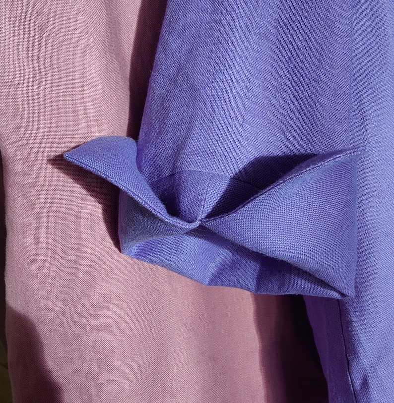 May include: Close-up of two fabric swatches, one a light purple and the other a darker purple. The darker purple fabric is folded over the lighter purple fabric.