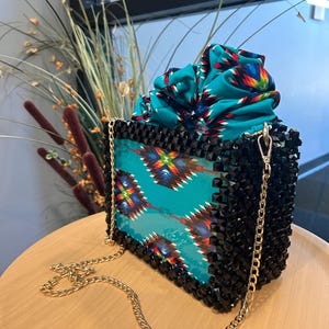Bolso Kente Kaima hecho a mano con cuentas para mujeres y niñas. Elegante acabado negro con base de acrílico y asa de cadena.