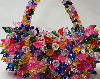 May include: A colorful handbag made of small, spiky, clear plastic beads in various colors, including red, orange, yellow, green, blue, purple, and pink.