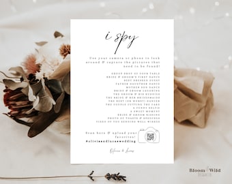 May include: A white card with black text that says "i spy" and lists a variety of wedding-related activities to photograph. The card also includes a QR code and the hashtag #oliviaandlucaswedding.