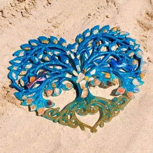 May include: A blue and gold tree of life wall decor with a heart shape at the base. The tree is decorated with small shells and has a blue bird perched on a branch.