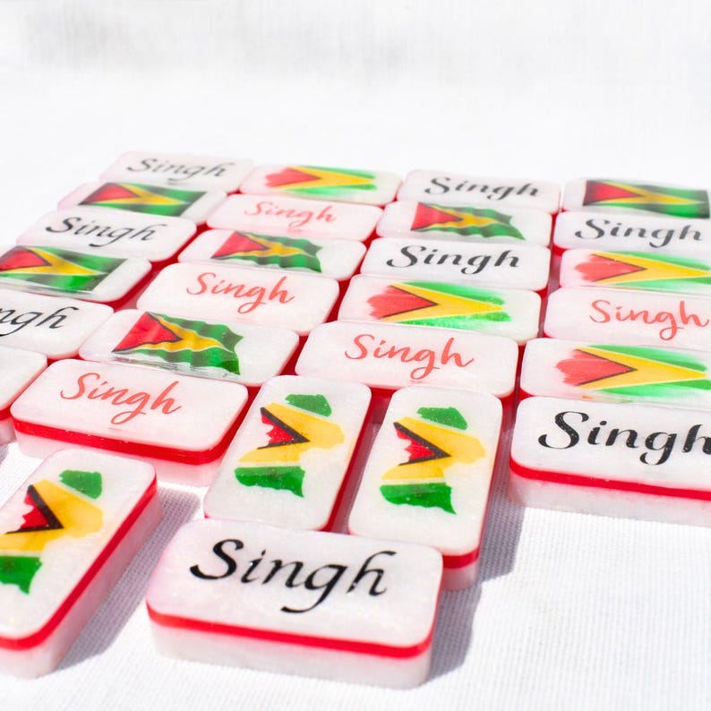 May include: Rectangular white objects with red borders and the name "Singh" in cursive. Each object features a colorful flag design with red, yellow, green, and black elements. The objects are arranged on a white surface.