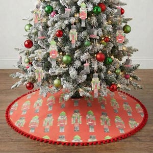 May include: A decorated Christmas tree with red, green, and silver ornaments, and nutcracker-themed tree decorations. The tree sits on a red tree skirt with a repeating nutcracker soldier pattern and a red pom-pom trim.