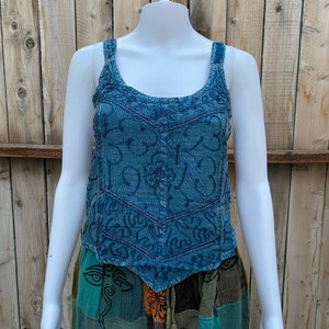May include: A blue sleeveless top with embroidered details. The top is made of a soft, textured fabric and has a relaxed fit.