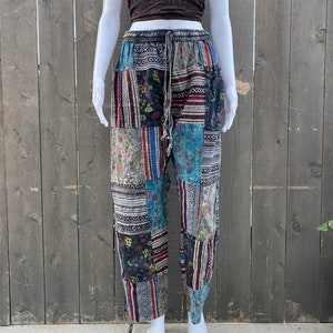 May include: Patchwork pants with a blue, red, and black color scheme. The pants have a drawstring waist and a relaxed fit.