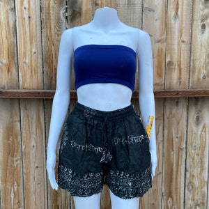 May include: Black and white printed shorts with a stretchy waistband. The shorts have a pattern of Sanskrit writing and other symbols. The shorts are being modeled on a white mannequin.