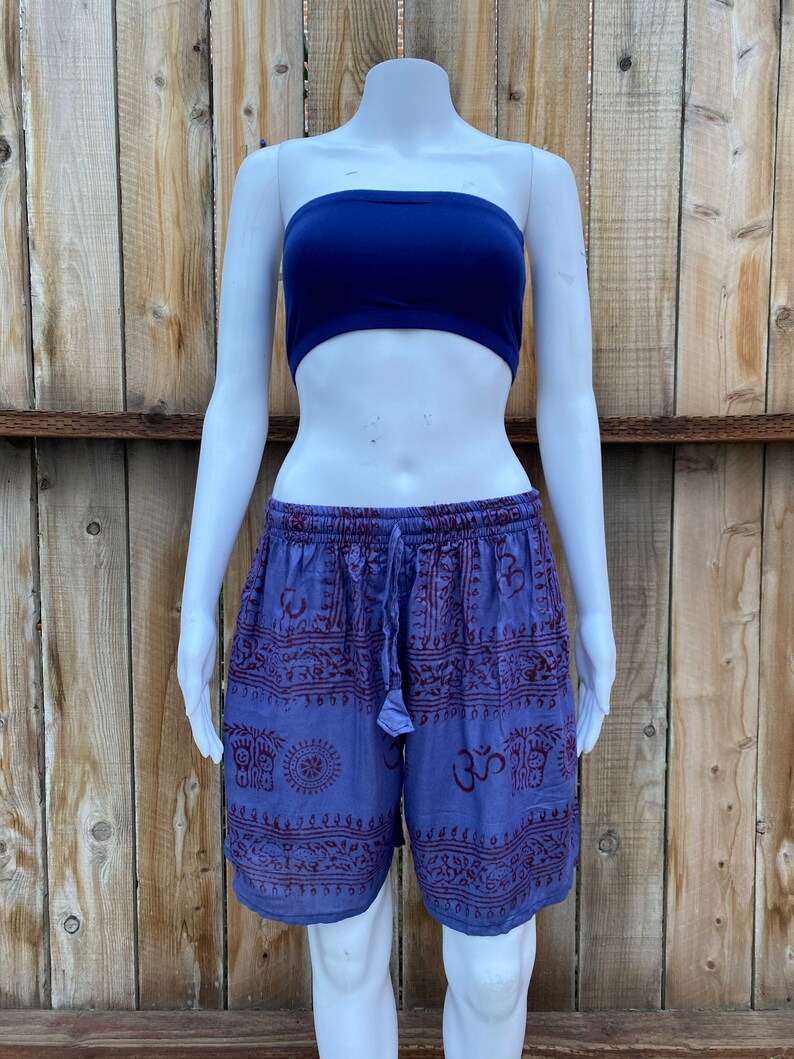 May include: Purple and red patterned shorts with a drawstring waist. The pattern includes various symbols and designs.