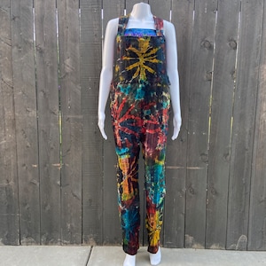 Op de afbeelding: Tie-dye denim overall in tinten van blauw, rood, geel en groen. De overall heeft een wijde pijp en een ontspannen pasvorm.
