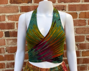 May include: A green, orange, and purple tie-dye halter top with a wrap style. The top is worn over a multi-colored patchwork skirt.