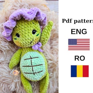 May include: Crocheted amigurumi turtle toy with a purple flower on its head. The toy is green and has a light green shell. The pattern is available in English and Romanian.
