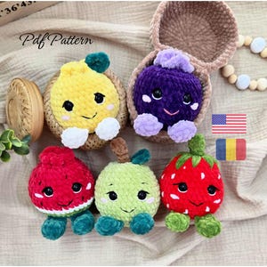 Può includere: Cinque giocattoli all'uncinetto a forma di frutta: un limone giallo, un'uva viola, un'anguria rossa, una mela verde e una fragola rossa. Ogni peluche ha occhi neri, un sorriso ricamato e piccoli arti. Il testo riporta Pdf Pattern.
