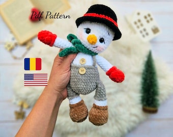 May include: A handmade crochet snowman doll with a black hat, red mittens, and a green scarf. The snowman has a carrot nose and button eyes. The doll is wearing gray overalls and brown boots. The text "Pdf Pattern" is visible in the image.