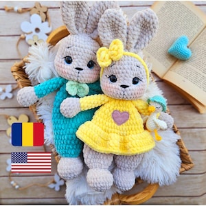 Puede incluir: Dos muñecas de conejito hechas a mano con ganchillo. Una conejita viste un atuendo turquesa con una pajarita verde, la otra un vestido amarillo con un corazón rosa. También hay un pequeño patito de ganchillo. Las muñecas están en una cesta tejida.