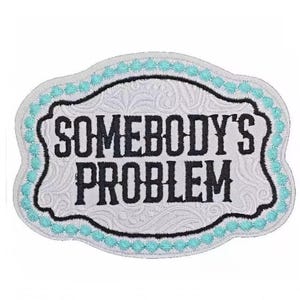 May include: Embroidered patch with the text "SOMEBODY'S PROBLEM" in black, set against a white background with a floral design. The patch has a black border and a turquoise scalloped edge.
