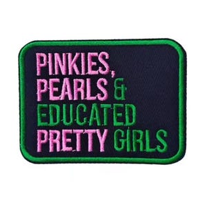May include: A rectangular patch with a dark blue background and a green border. The patch features the words "PINKIES, PEARLS & EDUCATED PRETTY GIRLS" in pink and green embroidered lettering.