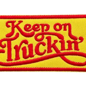 May include: Embroidered patch with the phrase "Keep on Truckin'" in red script on a yellow background. The patch has a red border. This patch is likely for a jacket, bag, or other apparel.