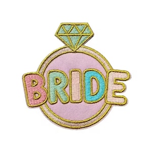May include: Embroidered patch featuring a ring design with a diamond and the word "BRIDE" in colorful letters. The ring is outlined in gold, with a light pink background. The diamond is light green.