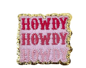 May include: A pink patch with the word "HOWDY" embroidered in red, with a gold glitter border. The word is stacked three times, with each word in a slightly different shade of pink.