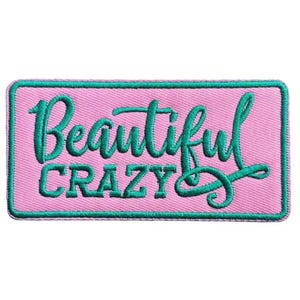 May include: A rectangular patch with a pink background and a teal border. The patch features the words "Beautiful" in cursive and "Crazy" in block letters, both in teal.