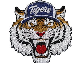 May include: A sequined tiger patch with a navy blue baseball cap that reads "Tigers" in white script. The tiger has a gold, black, white, and red color scheme, with an open mouth and visible teeth.