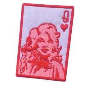 May include: Embroidered patch featuring a red and white design of a playing card. The card depicts the Queen of Hearts, with a portrait of a woman with red hair and the heart symbol. The patch has a red border.