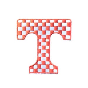 May include: Embroidered patch in the shape of the letter "T". The patch features a checkerboard pattern of orange and white squares. The patch is likely for apparel or accessories.