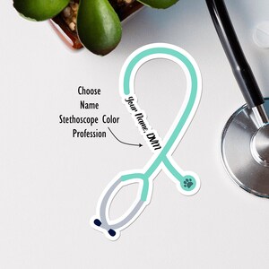 Puede incluir: Una pegatina de estetoscopio azul turquesa con una huella de pata y el texto "Your Name, DVM".