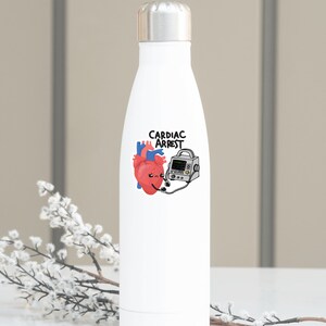 May include: White stainless steel water bottle with a cartoon heart and a defibrillator with the text "Cardiac Arrest" printed on it.