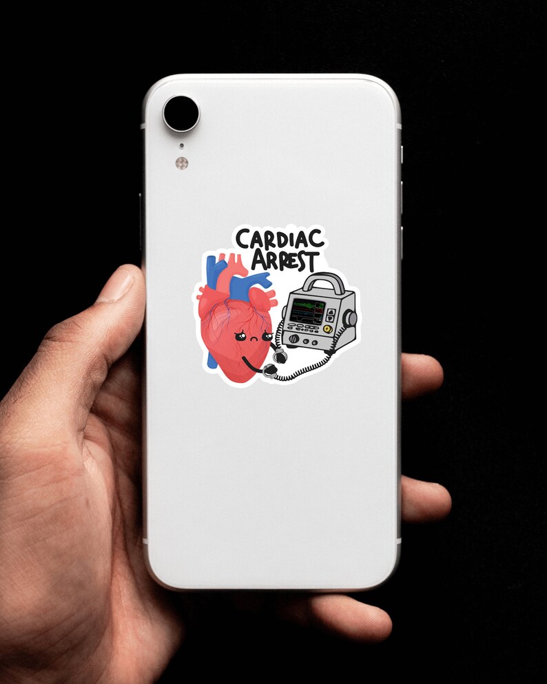 May include: A white phone case with a sticker of a cartoon heart attached to a defibrillator. The sticker says "Cardiac Arrest".