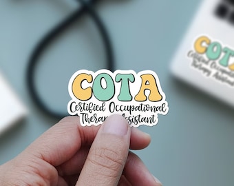Pode incluir: Um adesivo com o texto "COTA Certified Occupational Therapist Assistant" em uma fonte manuscrita colorida. As letras COTA estão em letras grandes, em negrito, com forma de bolha, com contorno amarelo e preenchimento azul claro. O restante do texto está em preto.