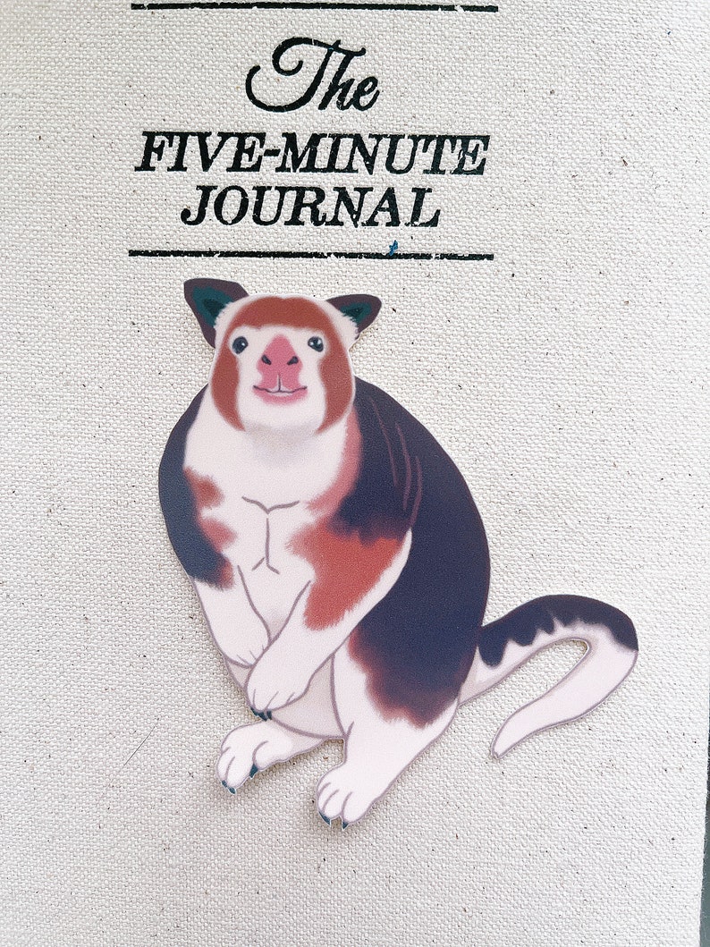 May include: A cartoon illustration of a red, white, and black animal with a long tail. The animal is sitting on a white background with the text "The Five-Minute Journal" above it.