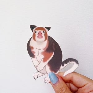 May include: A sticker of a cartoon red-nosed, white and brown, furry animal with a long tail. The animal is sitting upright with its paws in front of it.