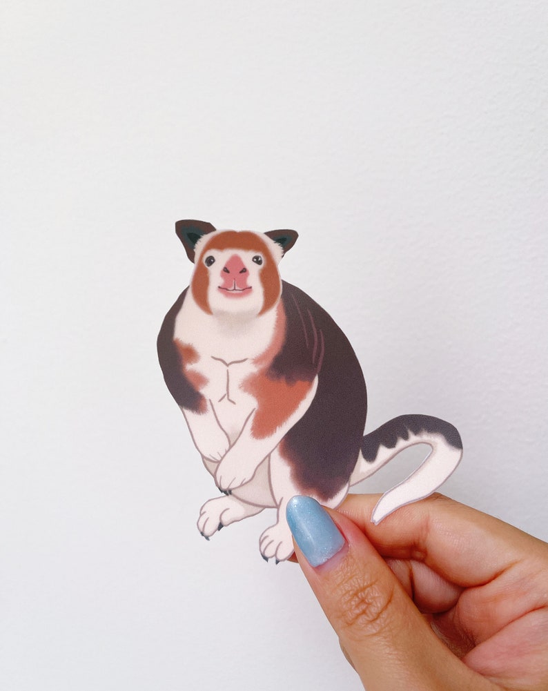 May include: A sticker of a cartoon red-nosed, white and brown, furry animal with a long tail. The animal is sitting upright with its paws in front of it.
