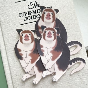 May include: Three cartoon stickers of a white and brown animal with black markings. The animal has a long tail and a round body. The stickers are on a white background with the text "The Five-Min Journ" visible.