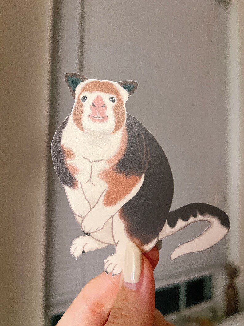 May include: A sticker of a cartoon kangaroo with brown, white, and black fur. The kangaroo is standing on its hind legs with its front paws tucked in. It has a pink nose and a friendly expression.