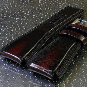 May include: Two dark brown leather watch straps with stitching detail. One strap has a metal buckle.