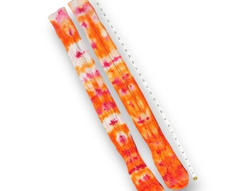 May include: A pair of long, orange and pink tie-dye socks. The socks are made of a soft, comfortable material and have a relaxed fit.